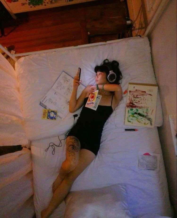 Overhead mood reference of a young woman listening to music in bed.