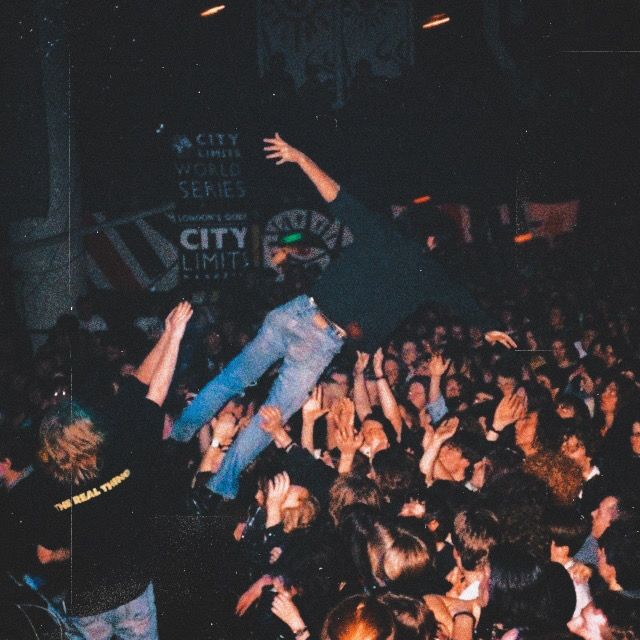 A crowded hardcore show, with a fan lifted above the audience.