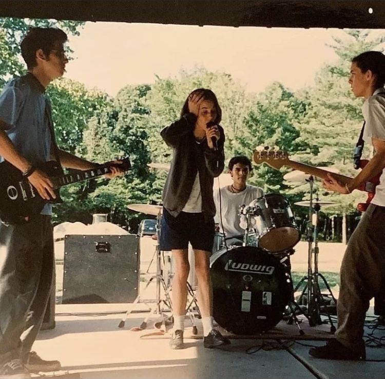 A band practicing together in an open garage.