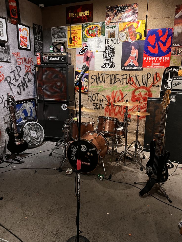 A punk rehearsal room packed with amplifiers, instruments and gig posters.