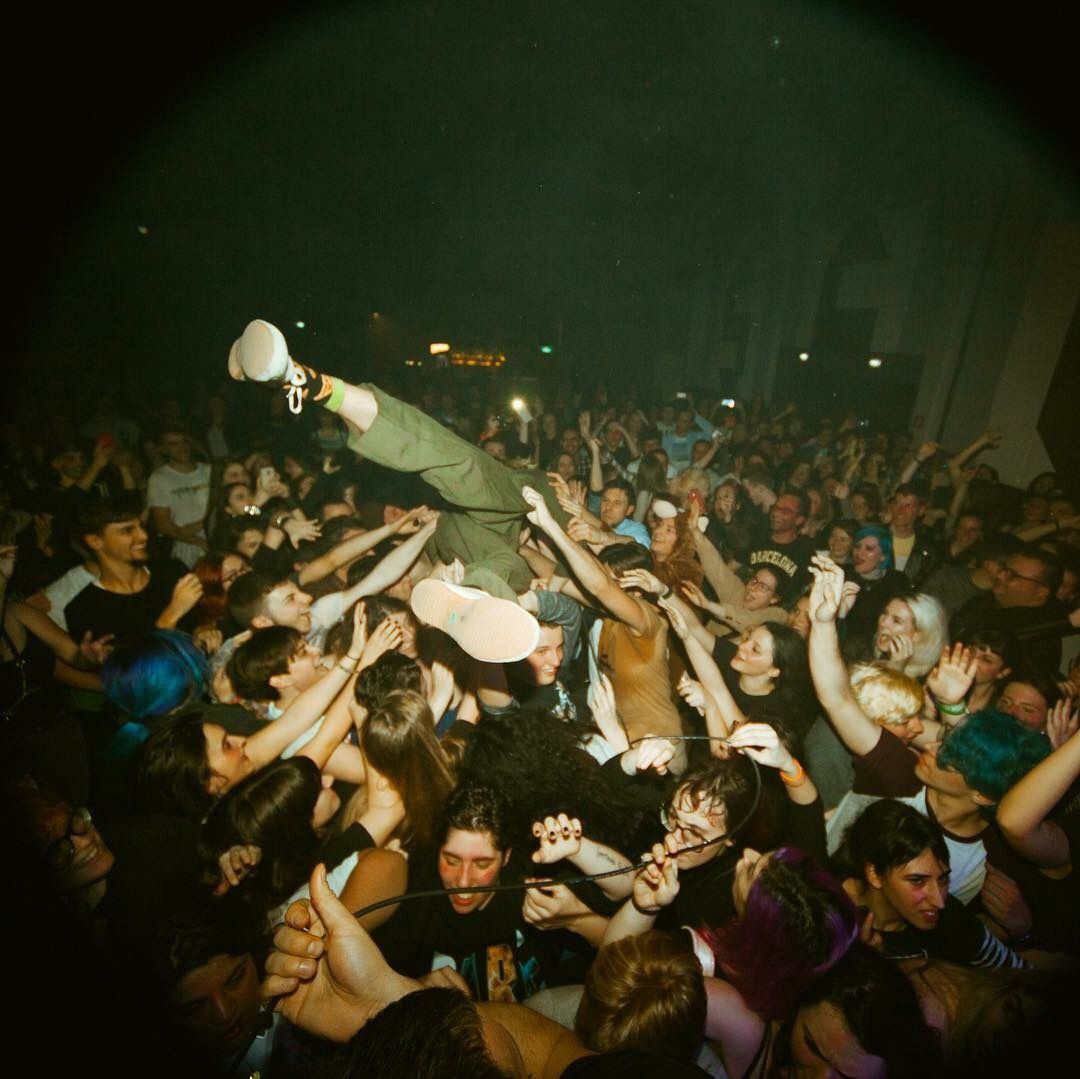 A crowd lifting a stage-diver at a hardcore show.
